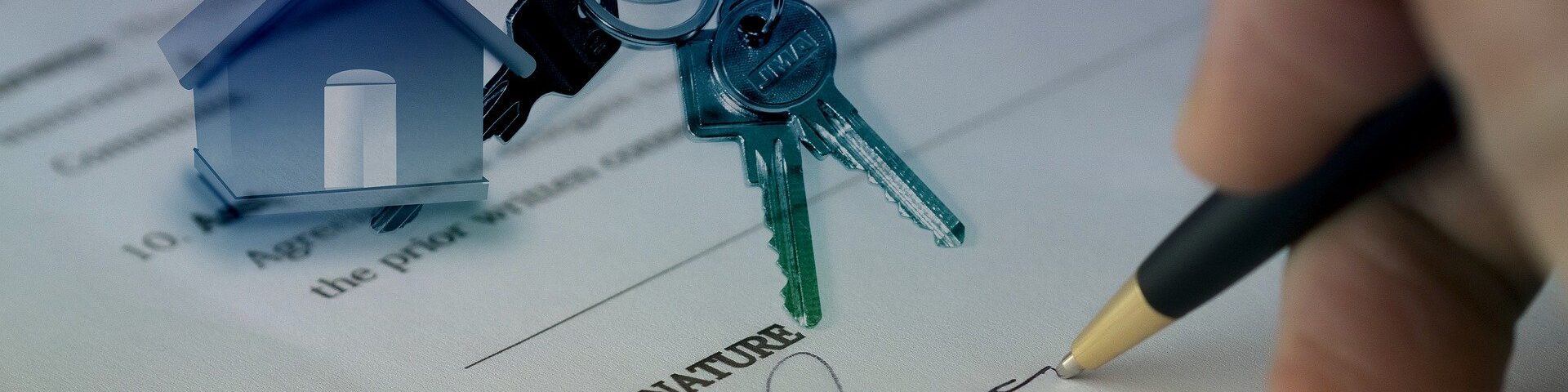 Caneta assinando um contrato e chaves em cima do papel