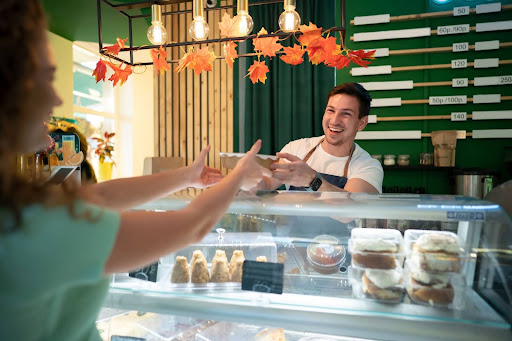 homem sorridente com um avental entregando um bolo a cliente